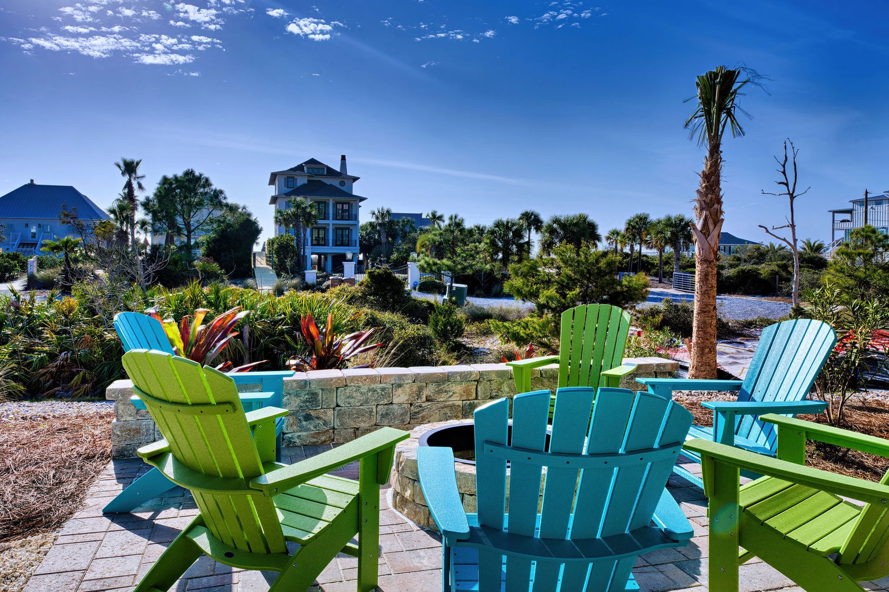 Stone fire pit surrounded by colorful Adirondack chairs at Sanctuary at Cape San Blas
